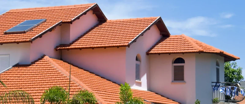 A house featuring a red tiled roof complemented by solar panels on top.