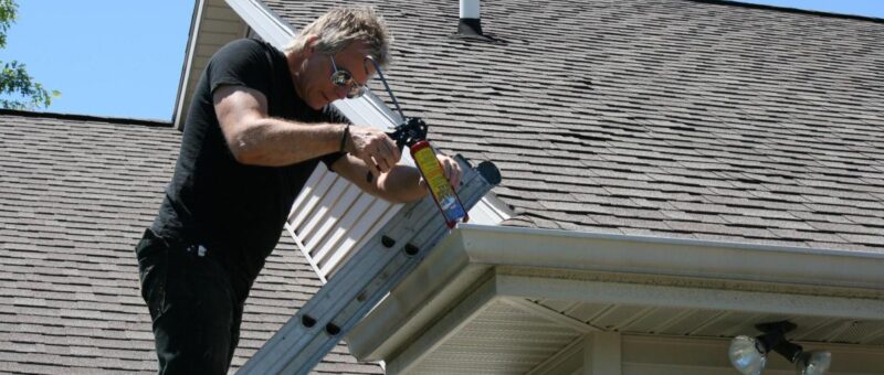 A man repairs a roof using a ladder, illustrating quick and easy methods to fix leaks and prevent damage.